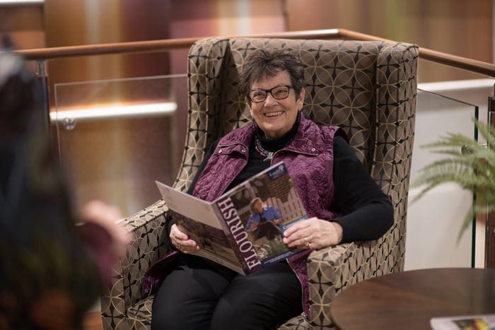 Resident in chair reading Flourish publication