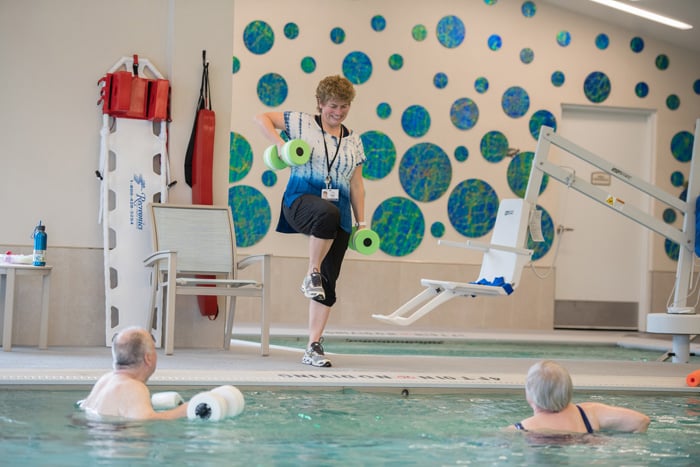 Seniors exercising in pool with instructor