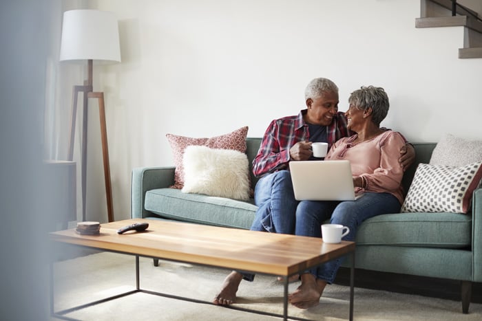 Senior couple on sofa using laptop