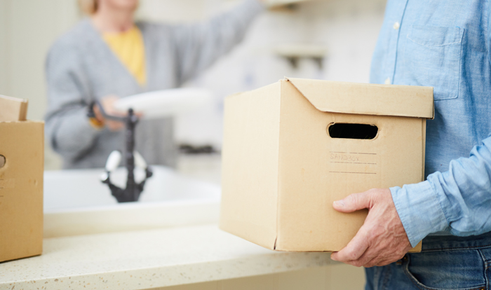 Senior man carrying heavy carton box.