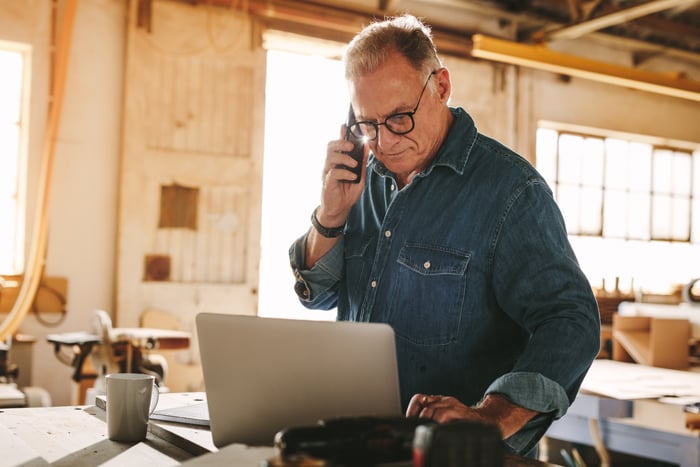 Man on laptop in wood shop