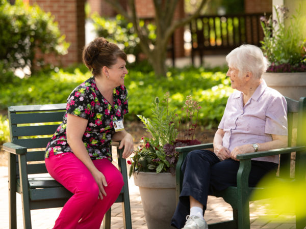 Two women talking together at one of Landis Homes outdoor sitting areas.