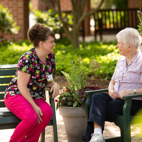 Two women talking together at one of Landis Homes outdoor sitting areas.