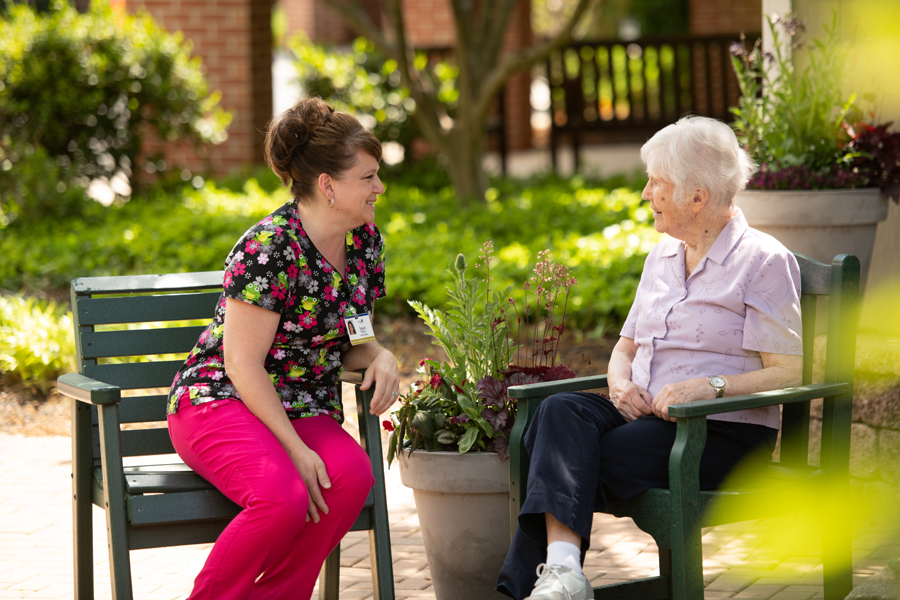 Two women talking together at one of Landis Homes outdoor sitting areas.