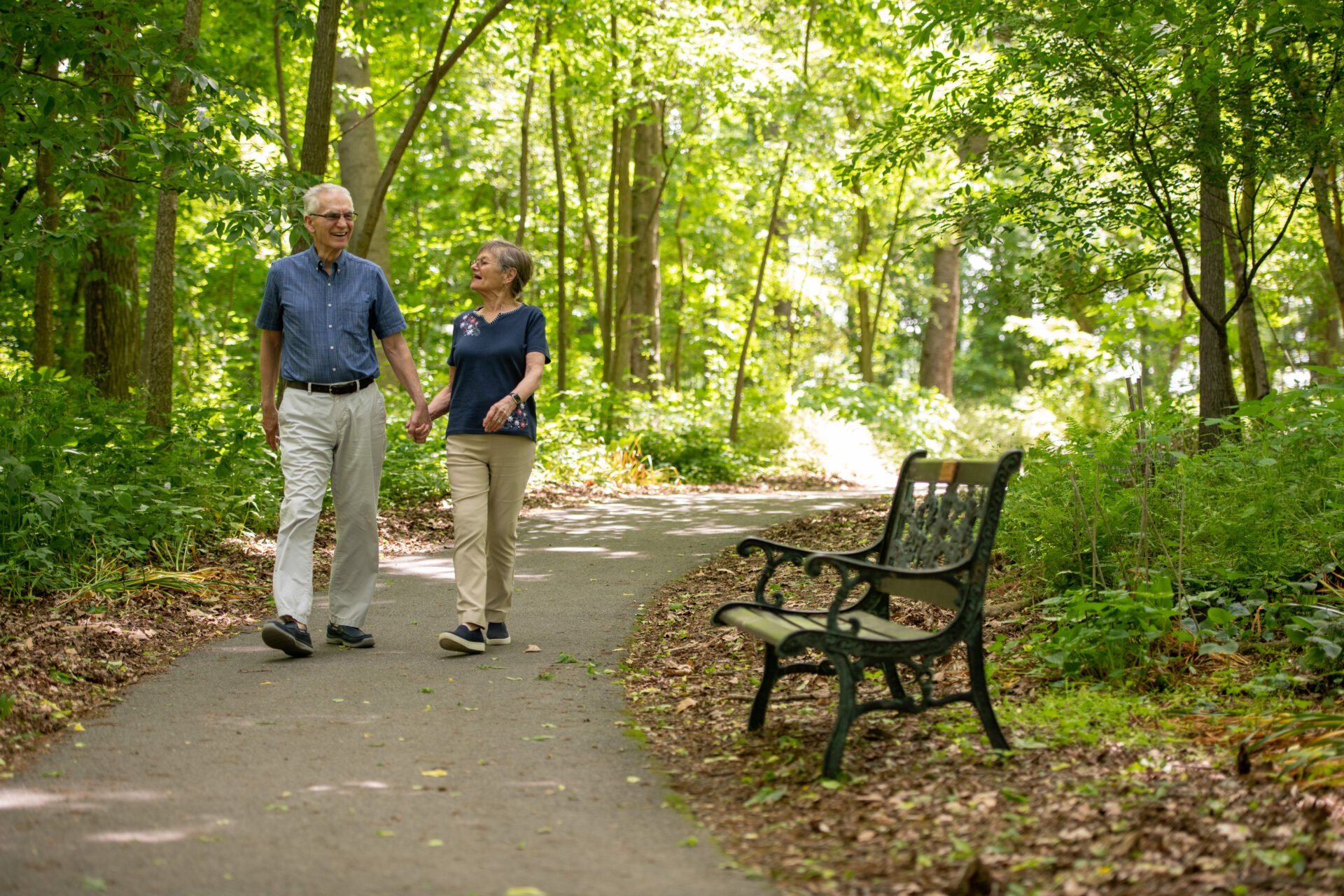 Senior couple walking down a shaded trail.